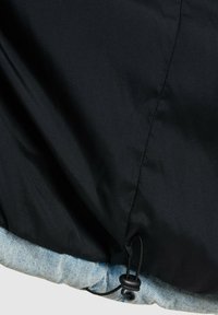 Crna jakna s donjim rubom od trapera, glatkom teksturom i vezicom u struku za prilagodljivu veličinu.