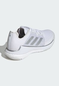 Scarpe sportive bianche con tomaia in tessuto testurizzato, caratterizzate da tre strisce grigie, un colletto imbottito e una suola in gomma bianca spessa.