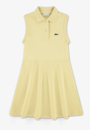 Robe polo en coton jaune clair avec un design sans manches, un col à revers et une jupe évasée. Présente un détail de logo vert.