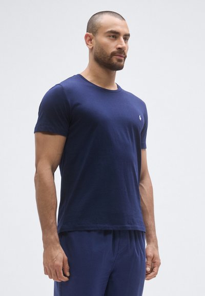 Tmavomodré bavlnené tričko s okrúhlym výstrihom a krátkymi rukávmi, s malým logom na hrudi. Hladká textúra a priliehavý strih.
