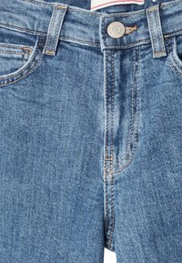 Jeans in denim blu con un classico design a cinque tasche, caratterizzati da cuciture chiare e una chiusura con bottone metallico in vita.