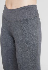 Szare legginsy w wysokim stanie wykonane z miękkiego, elastycznego materiału z płaskimi szwami i gładką fakturą, z dopasowanym krojem.