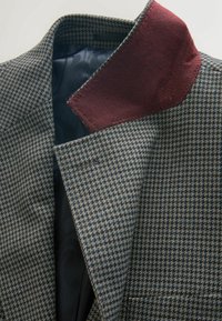 Houndstooth patterned jacket in gray and brown fabric with a burgundy collar accent. Interior lined with dark patterned fabric.