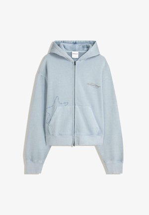 Lyseblå zip-up hættejakke med hætte, forlommer og et stjernedesign på venstre side, lavet af blødt, struktureret stof.