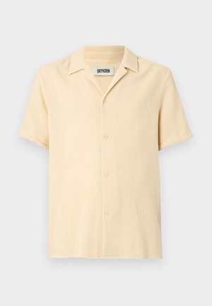 Cămașă cu mânecă scurtă, cu nasturi, de culoare bej deschis, cu un design texturat și țesut. Prezintă un guler cu decupaj și un tiv drept.