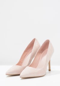 Beige mocka högklackade pumpar med spetsig tå och minimalistisk design. Har en smal klack och slät innersula.