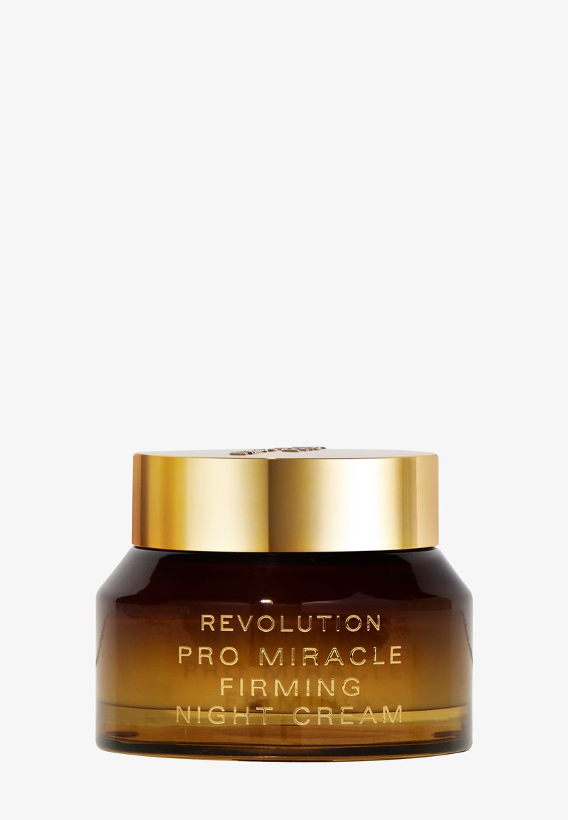 Brun glasskrukke med et gullokk, merket "Revolution Pro Miracle Firming Night Cream" i relieffbokstaver. Glatt, avrundet form.