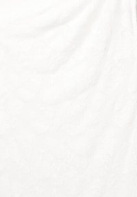 Bílá látka s texturovaným květinovým vzorem, která obsahuje vyvýšené motivy, jež vytvářejí hloubku a vizuální zajímavost. Hladký povrch, jemný finiš.