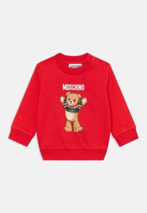 Rød sweatshirt til småbørn med ribbede manchetter og krave, med en teddybjørn iført en julekrans og teksten "MOSCHINO" ovenover.