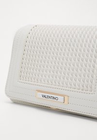 White leather clutch with textured woven pattern on the front, featuring a gold hardware plaque labeled "VALENTINO" at the bottom.