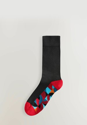Schwarze Socke mit einem gerippten Bündchen, die ein buntes geometrisches Muster am Fuß aufweist, akzentuiert mit roten, blauen und orangefarbenen Abschnitten.
