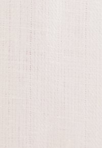 Gros plan d'un tissu tissé beige clair montrant une texture détaillée avec de petits fils espacés uniformément et des lignes verticales et horizontales subtiles.