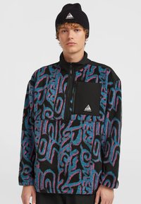 Pull en polaire noir, bleu et rose à motif abstrait, avec une demi-fermeture éclair, un col montant et une poche poitrine avec accent noir.