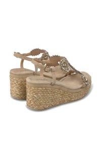 Sandales compensées beiges avec une semelle en corde tissée, ornées de strass transparents sur une bride en T. Matière en daim doux.