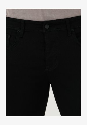 Jeans de mezclilla negra con una textura suave, diseño de cinco bolsillos y cierre de un solo botón. La costura contrasta ligeramente con la tela.