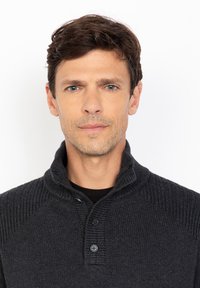 Ciemnoszary sweter z dzianiny o prążkowanej fakturze, z zagiętym kołnierzem i trzema guzikami. Tło jest gładkie, białe.