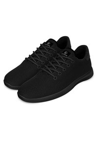 Schwarze Sportschuhe aus strukturiertem Mesh-Stoff, mit flachen Schnürsenkeln, einem schlanken Design und einer niedrigprofilierten Gummisohle.
