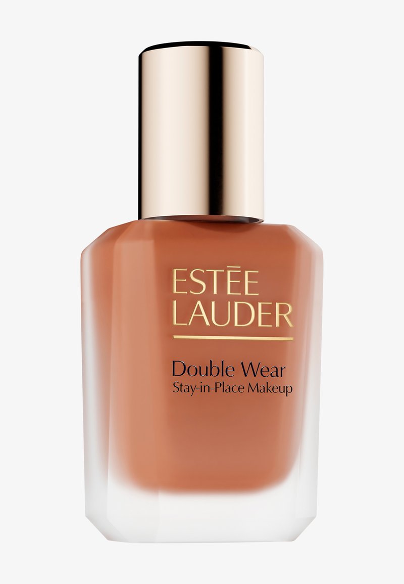 Fond de teint Estée Lauder Double Wear dans un flacon en verre brun avec un bouchon doré. La base est légèrement givrée, avec un texte noir pour la marque.