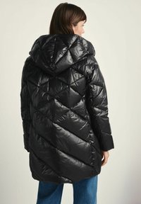 Czarna kurtka puchowa z kapturem, o błyszczącej powierzchni, z pikowaniem w kształcie diamentów oraz długimi rękawami. Model ma długość do połowy uda.