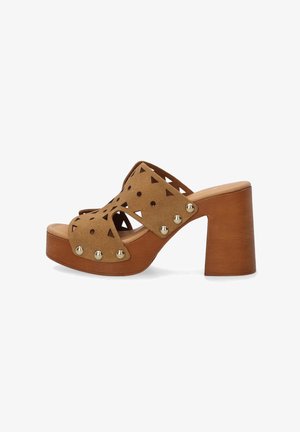 Sandales compensées en daim marron avec des motifs triangulaires découpés, des accents de clous en or et un talon en bois épais. Design à bout ouvert et sans dos.