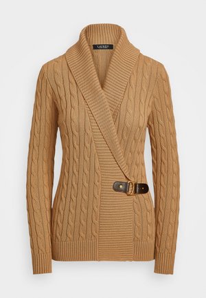 Tan cable-knit sweater with a shawl collar, asymmetrical design, featuring a brown buckle detail on the left side and ribbed cuffs.