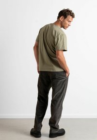 Olivenfarget t-skjorte med korte ermer kombinert med mørkegrå cordpants. Stoffet ser mykt ut med en avslappet passform og et enkelt design.