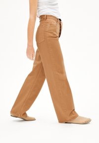 Pantalons larges marron clair en coton, avec une coupe droite, des coutures visibles et un design classique à cinq poches.