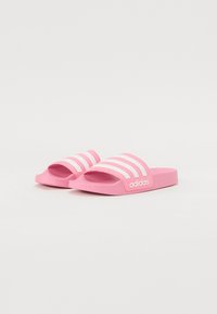 Ružičaste slide papuče s tri bijele pruge i "adidas" logotipom sa strane. Izrađene od izdržljive gume s glatkom teksturom.