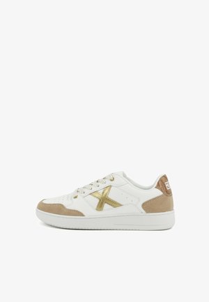 Witte lage sneaker met beige suède accenten, gouden metalen "X" aan de zijkant, witte veters en een gestructureerd bruin hielstuk.