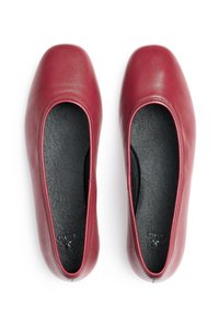 Rote Leder-Ballettschuhe mit runder Zehenpartie, die eine glatte Textur und ein schwarzes Innenfutter aufweisen. Keine sichtbaren Beschläge oder Muster.
