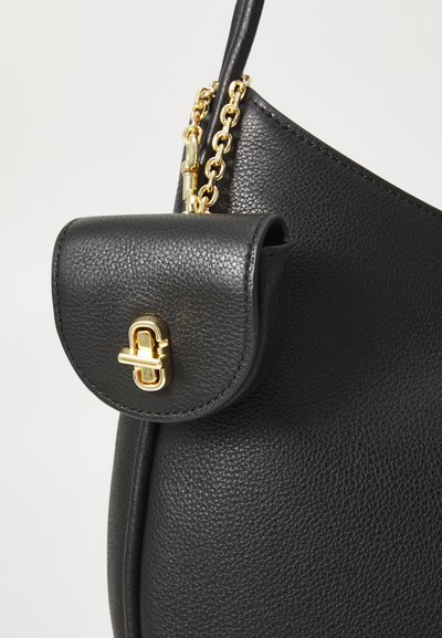 Black leather handbag featuring a textured finish, a structured shape, a gold chain handle, and a small flap pocket with a gold clasp.