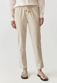 Pantalones a rayas en beige y crema con cintura ajustable con cordón, confeccionados en una tela ligera, con pierna ajustada y textura suave.
