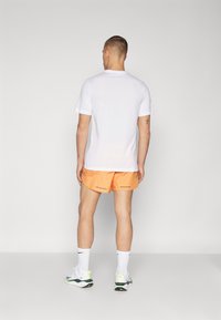 Nike Performance RUN STRIDE - Pantalón corto de deporte - bright mandarin/black
