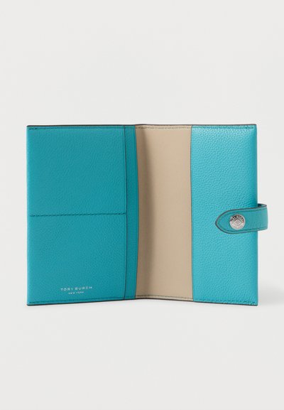Turquoise leren portemonnee met beige interieur, drukknoopsluiting en het logo "Tory Burch New York" gecodeerd aan de binnenzijde aan de linkerkant.
