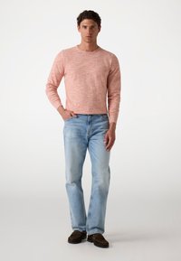 Cămașă lungă roz deschis cu un finisaj texturat, asortată cu blugi denim bleu deschis și mocasini maro. Design simplu și casual.