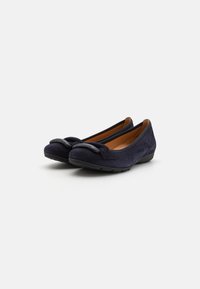 Ballerine in suede blu navy con punta tonda e un accento decorativo a nodo. Presentano una soletta imbottita e suola in gomma nera per una buona aderenza.