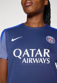 Navy blue sports jersey featuring a round neck, mesh texture, blue accents on shoulders, and white logos for Nike and Qatar Airways.