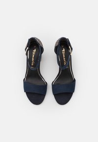 Sandali con tacco blu navy, con una fascia frontale in suede morbido, una cinghia alla caviglia e una parte posteriore texturizzata. Dettaglio in oro sulla fibbia.