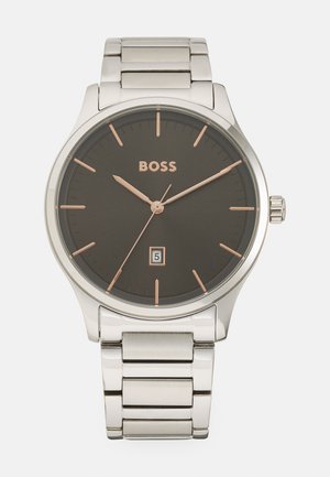 Montre en acier inoxydable argenté avec un cadran gris foncé, des accents en or rose, des index horaires et un affichage de la date à 6 heures, dotée d'un bracelet en maillons métalliques.