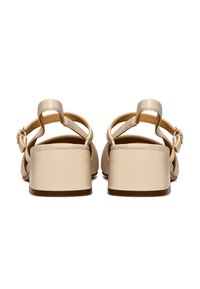 Sandali con tacco blocco beige, realizzati con una tomaia in pelle liscia, sottili cinturini alla caviglia e un piccolo dettaglio in metallo a forma di fibbia sul retro.