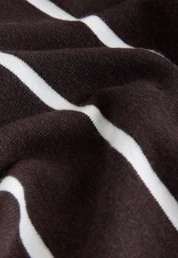 Mörkbrunt tyg med en mjuk struktur och horisontella vita ränder. Materialet verkar vara stickat och något texturerat.