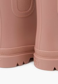 Stivali di gomma rosa con accenti texturizzati, design moldato e suole rigate. Presentano aperture laterali e dettagli di cucitura vicino al bordo superiore.