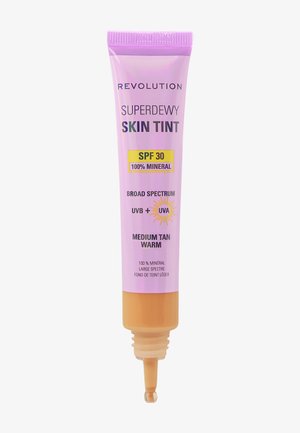 Revolution Superdewy Skin Tint, 50 ml tube, lyse lilla med gule og orange accenter, indeholder SPF 30, 100% mineralformel, nuance: medium tan varm.