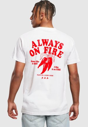 White cotton t-shirt featuring red text and chili pepper graphics on the back, with phrases about heat and spice. Regular fit.