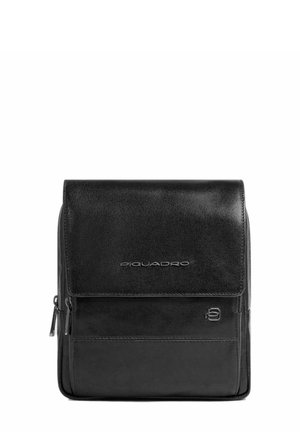 Bolsa de mensajero de cuero negro con cierre de solapa, bolsillo frontal con cremallera, logo grabado y textura suave. Forma rectangular compacta.