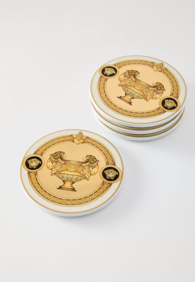 Díszítő porcelántányérok készlete, arany és krémszínű kialakítással, bonyolult oroszlánmotívumokkal és díszes szegélyekkel.