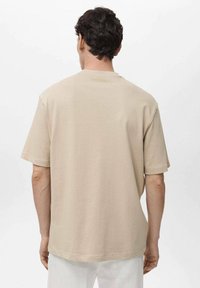 Tricou bej cu mânecă scurtă, realizat din bumbac moale, având o croială lejeră și un gât rotund. Design minimalist, fără detalii decorative.