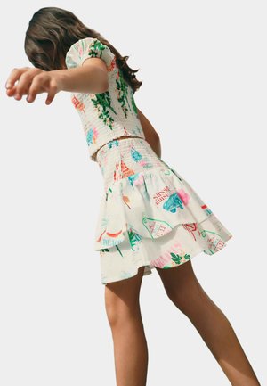 Completo a due pezzi composto da una blusa floreale arricciata e una gonna a strati con motivi in crema, decorata con grafiche colorate che richiamano il tema della spiaggia e delle palme.
