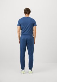 Μπλέ σκούρες φόρμες και μπλούζα από μαλακό ύφασμα. Οι φόρμες διαθέτουν δύο πίσω τσέπες και ελαστική μέση. Χαλαρή, άνετη εφαρμογή.