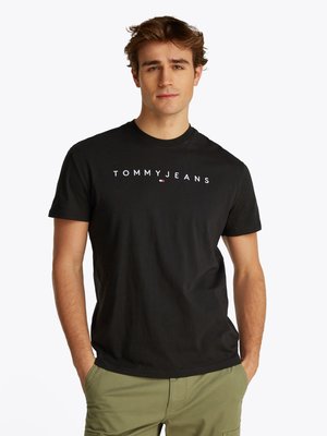 Schwarzes Baumwoll-T-Shirt mit weißem "TOMMYJEANS"-Logo. Rundhalsausschnitt-Design mit kurzen Ärmeln, kombiniert mit olivgrünen Cargo-Hosen.